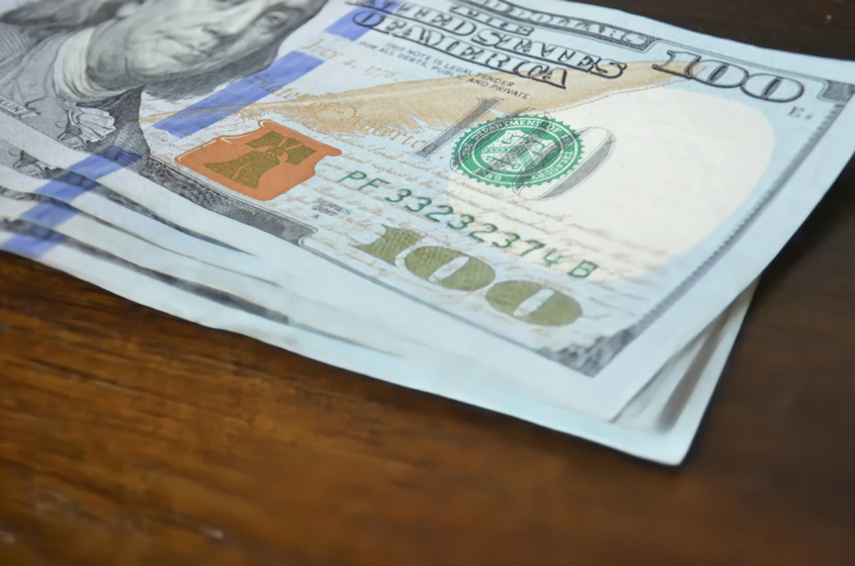 Stack of hundred dollar bills on a table representing a trading payout